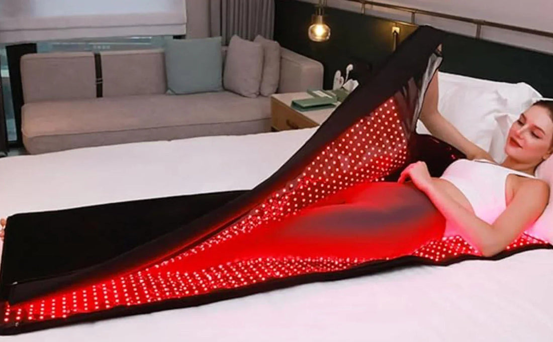Woman relaxing under red LED light therapy blanket for at-home skin treatment and recovery